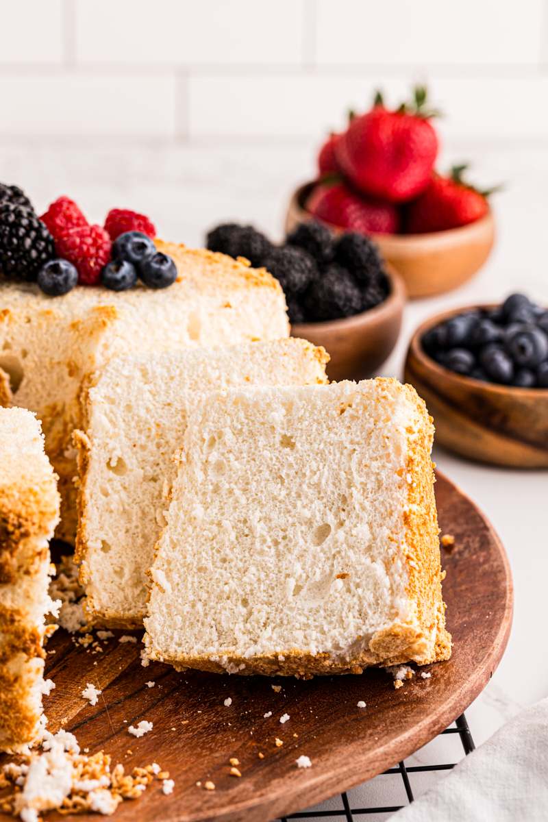 partially sliced angel food cake on a wooden cake plate