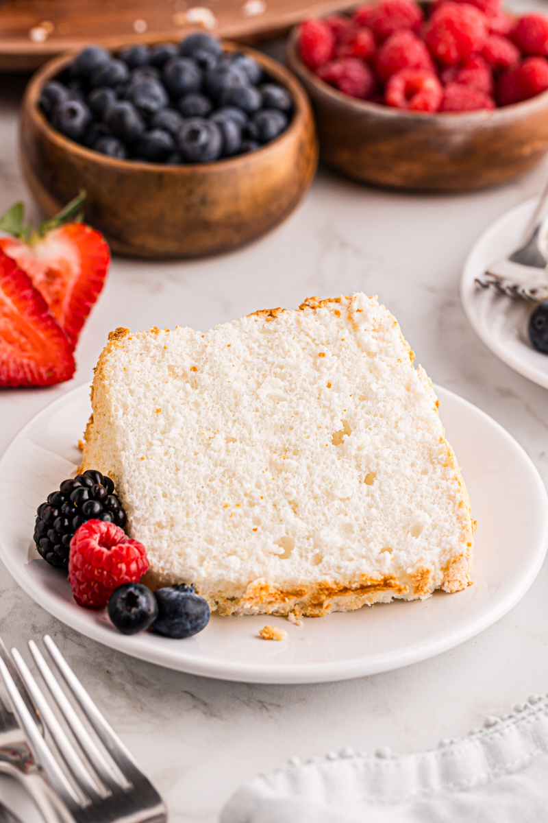 a slice of angel food cake on a white plate with fresh berries