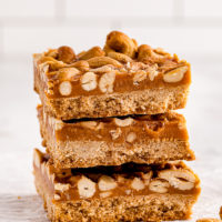 a stack of three butterscotch cashew bars on a marble surface