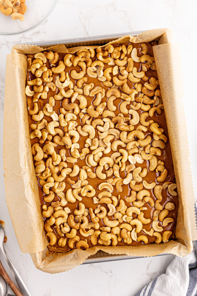 overhead view of cashews sprinkled over butterscotch filling for butterscotch cashew bars