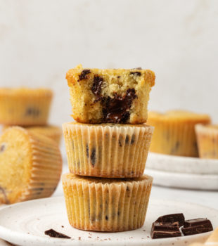 a stack of three chocolate chunk cupcakes with a bite missing from the top cupcake to show the chocolate filling and soft texture