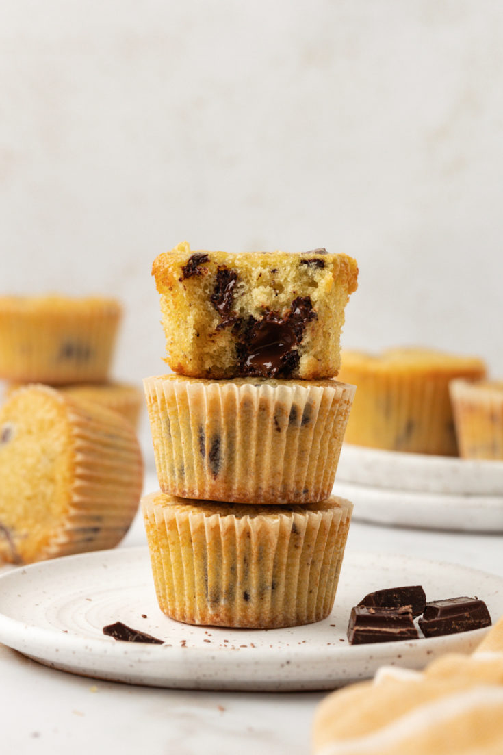 a stack of three chocolate chunk cupcakes with a bite missing from the top cupcake to show the chocolate filling and soft texture