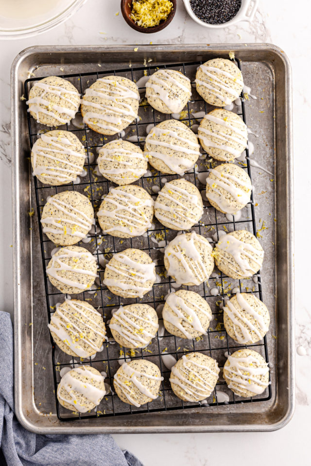 overhead view of glazed lemon poppy seed cookies on a wire rack over a baking sheet