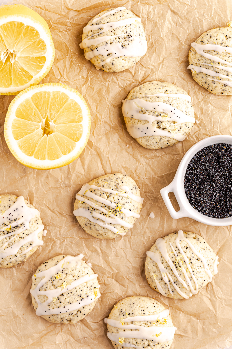 overhead view of lemon poppy seed cookies on parchment paper with lemon slices and a small bowl of poppy seeds