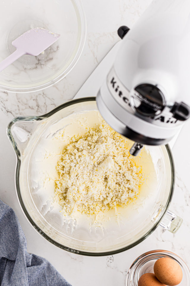 overhead view of sugar added to creamed butter in the bowl of a stand mixer