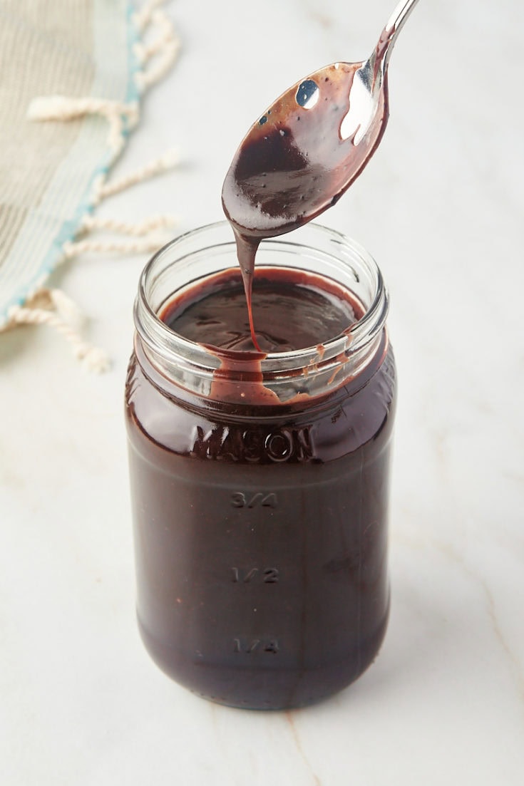 a spoonful of hot fudge sauce over a jar of sauce