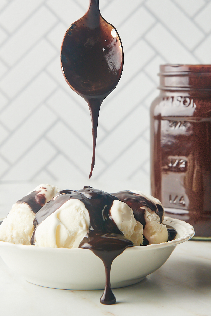 hot fudge sauce drizzling off a spoon onto a bowl of vanilla ice cream