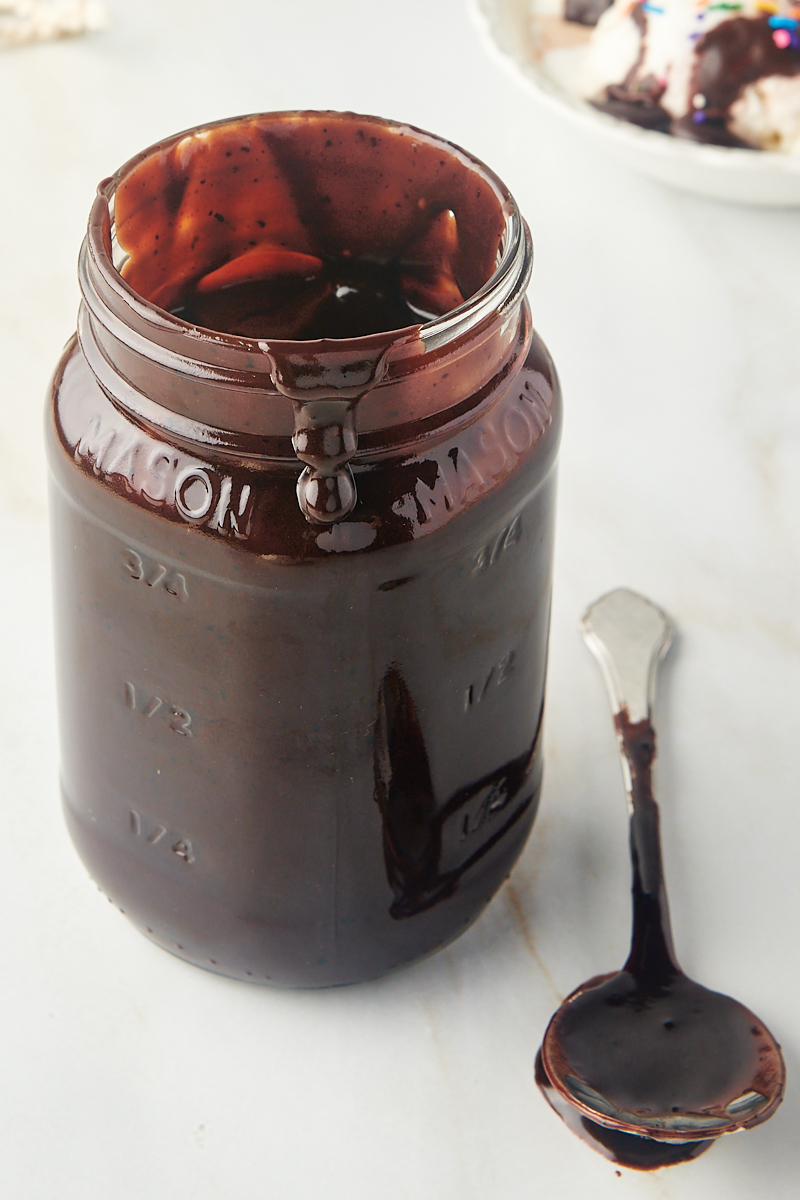 a jar of hot fudge sauce with a spoonful of sauce beside it