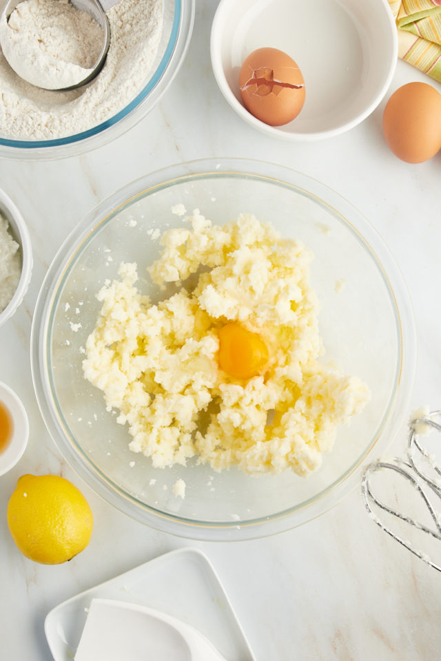 overhead view of egg added to creamed butter and sugar in a glass mixing bowl