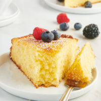 a slice of lemon ricotta cake on a white plate with a bite on a fork