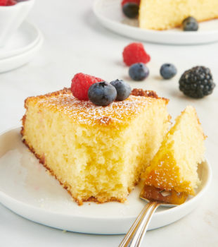 a slice of lemon ricotta cake on a white plate with a bite on a fork