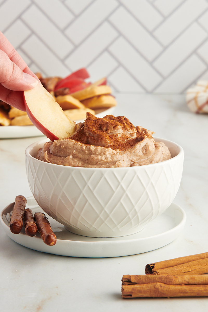 an apple slice dipping into a bowl of snickerdoodle cookie dip