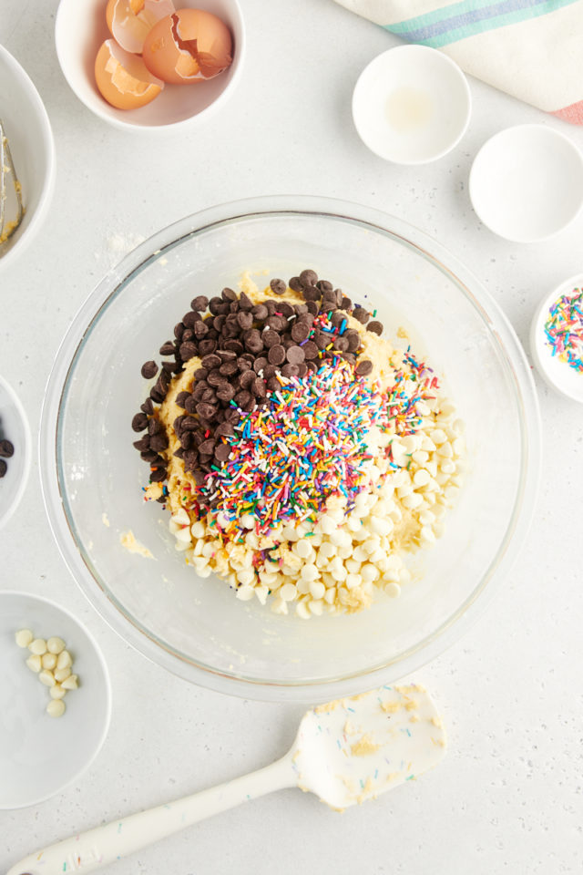 overhead view of chocolate chips and sprinkles added to cookie dough
