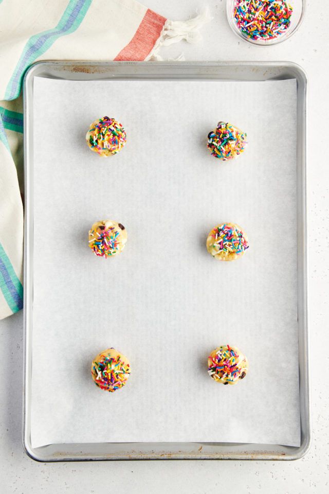 overhead view of sprinkle chocolate chip cookie dough balls on a parchment-lined baking sheet