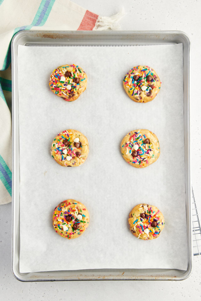 overhead view of freshly baked sprinkle chocolate chip cookies on a parchment-lined baking sheet