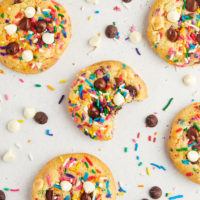 overhead view of sprinkle chocolate chip cookies scattered on a white countertop
