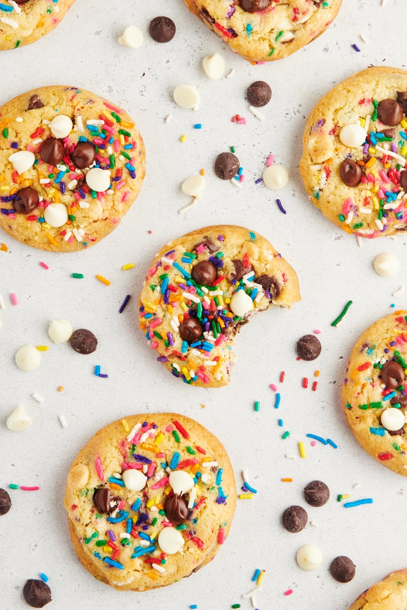 overhead view of sprinkle chocolate chip cookies scattered on a white countertop