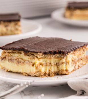 a slice of chocolate eclair cake with a bite missing from the front corner