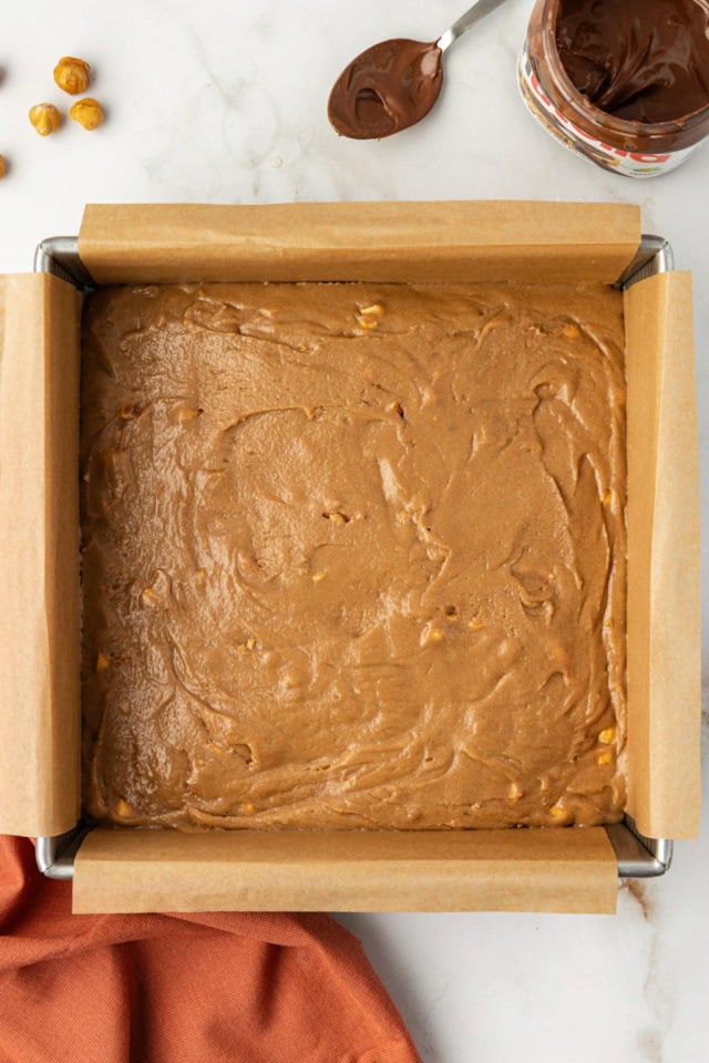 overhead view of hazelnut blondies batter spread in a square baking pan