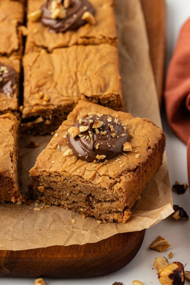 a hazelnut blondie on a cutting board with more blondies surrounding