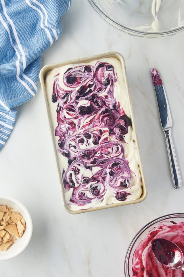 overhead view of layered and assembled blueberry cheesecake ice cream in a metal loaf pan