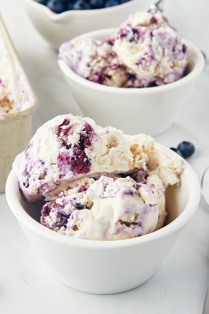 a bowl of blueberry cheesecake ice cream with another bowl of ice cream in the background