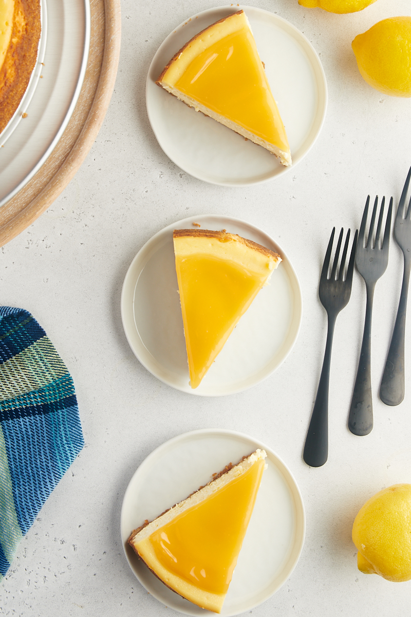 overhead view of three slices of lemon cheesecake on white plates