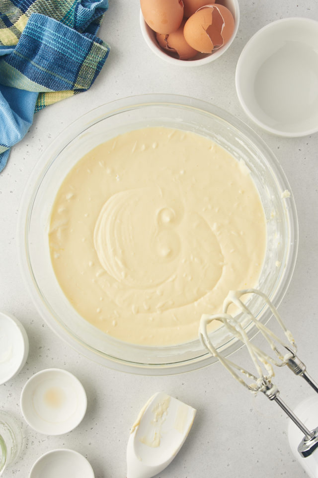 overhead view of mixed lemon cheesecake batter in a glass mixing bowl