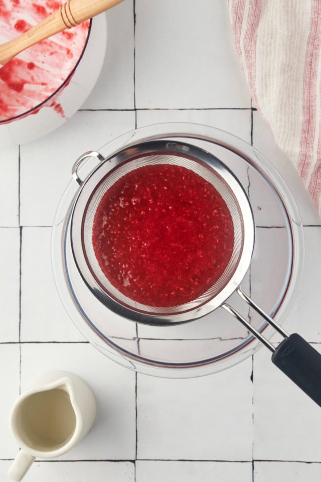 overhead view of raspberry coulis in a fine-mesh sieve