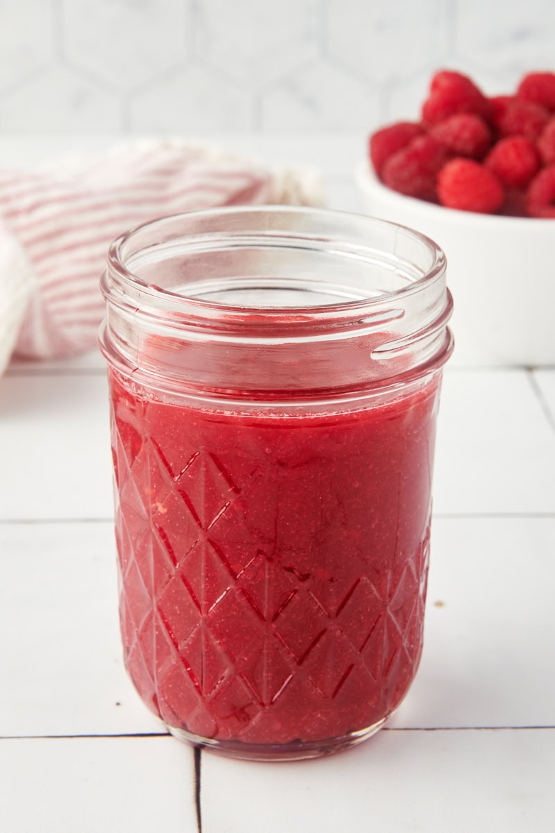 a glass jar filled with raspberry coulis