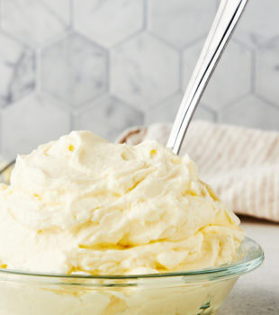 stabilized whipped cream in a glass bowl with a spoon sticking out
