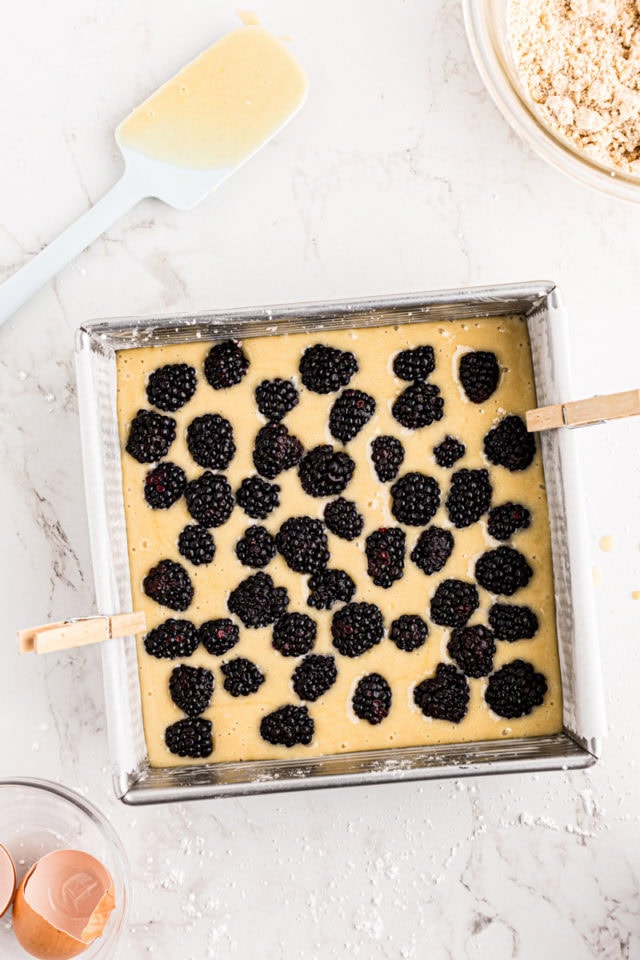 overhead view of blackberries added to blackberry crumb bars batter in a square baking pan