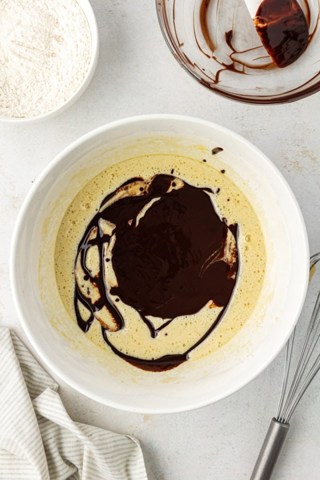 overhead view of chocolate mixture added to sugar mixture for chocolate chip cheesecake brownies