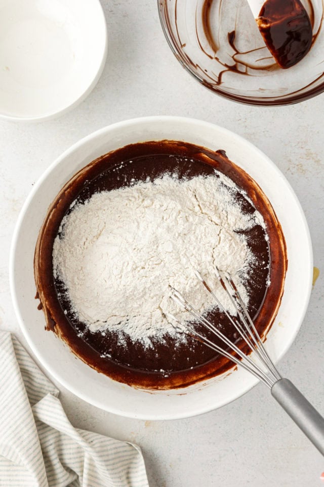 overhead view of dry ingredients added to brownie batter in a white mixing bowl