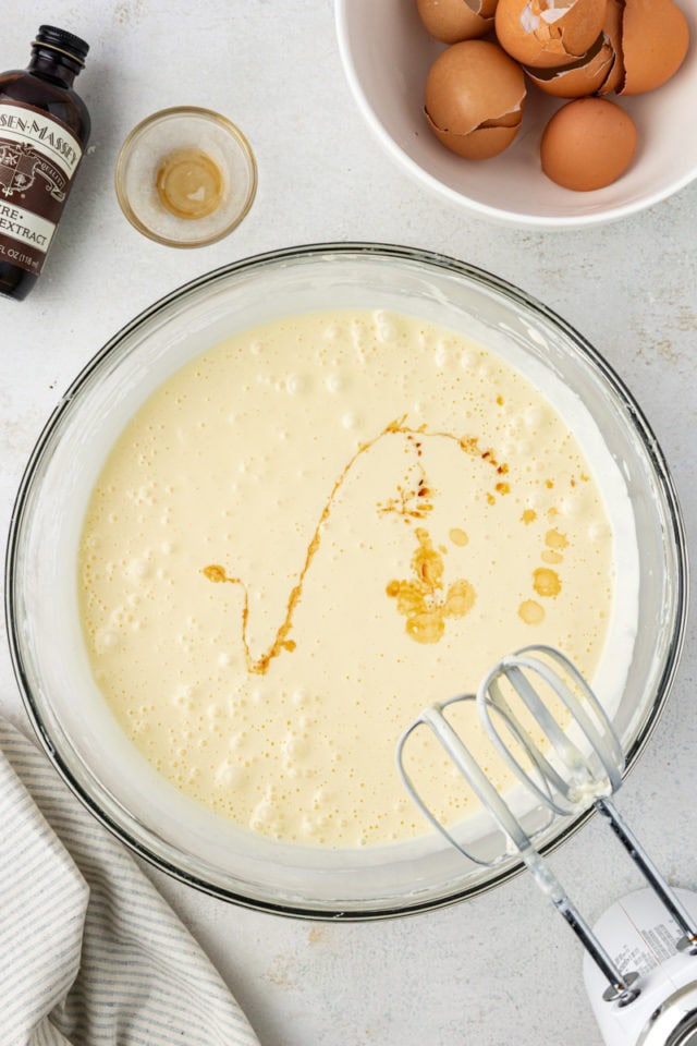 overhead view of vanilla added to cream cheese mixture for chocolate chip cheesecake brownies