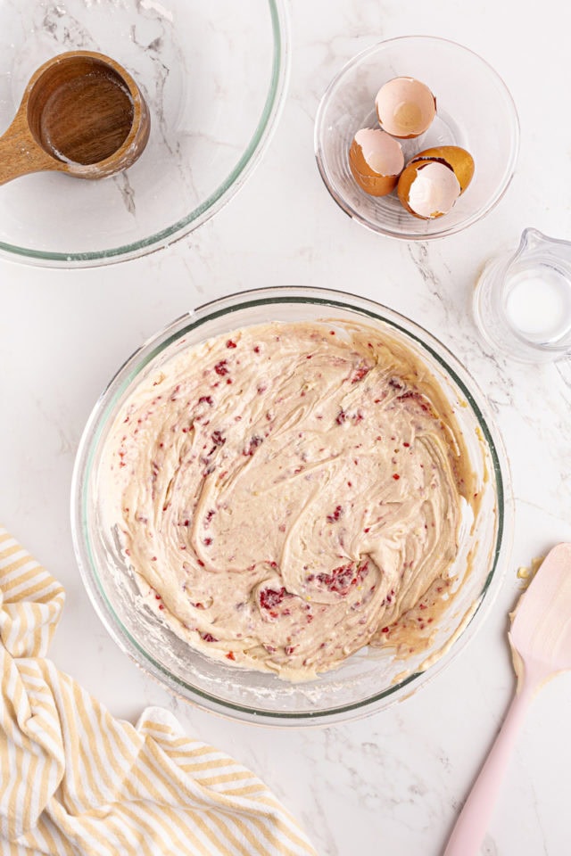 overhead view of mixed lemon raspberry cake batter in a glass mixing bowl