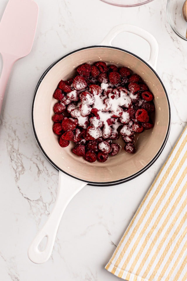 overhead view of raspberries, sugar, and lemon juice in a saucepan