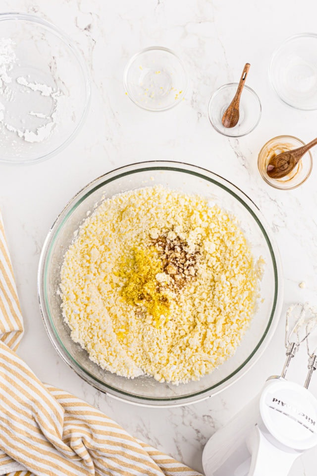 overhead view of vanilla extract, lemon juice, and lemon zest added to frosting mixture