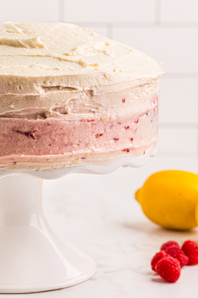 partial view of lemon raspberry cake on a white cake stand