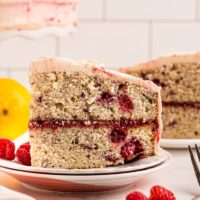 side view of a slice of lemon raspberry cake on a white plate