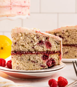 side view of a slice of lemon raspberry cake on a white plate