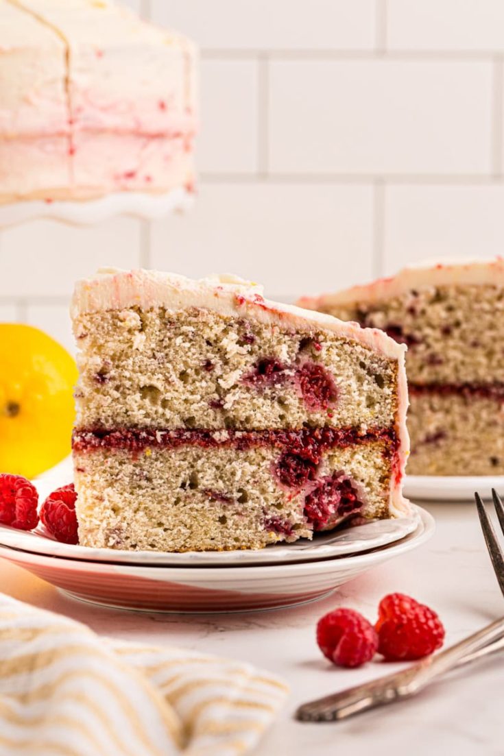 side view of a slice of lemon raspberry cake on a white plate