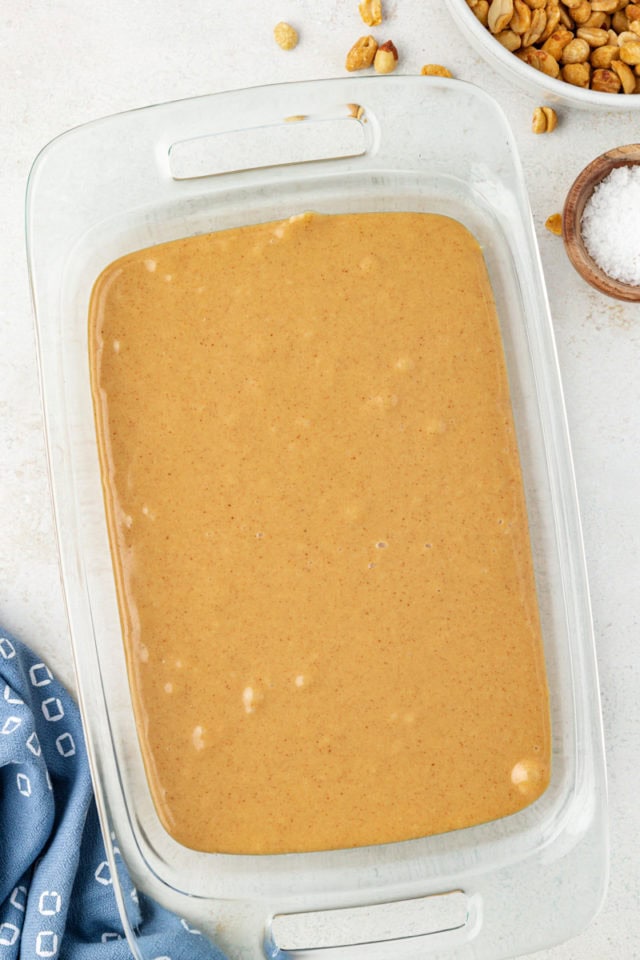 overhead view of peanut butter filling covering peanuts in a glass pan