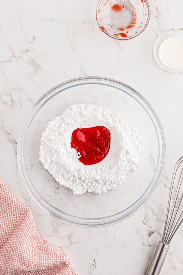 overhead view of confectioners' sugar, strawberry puree, and milk in a glass mixing bowl