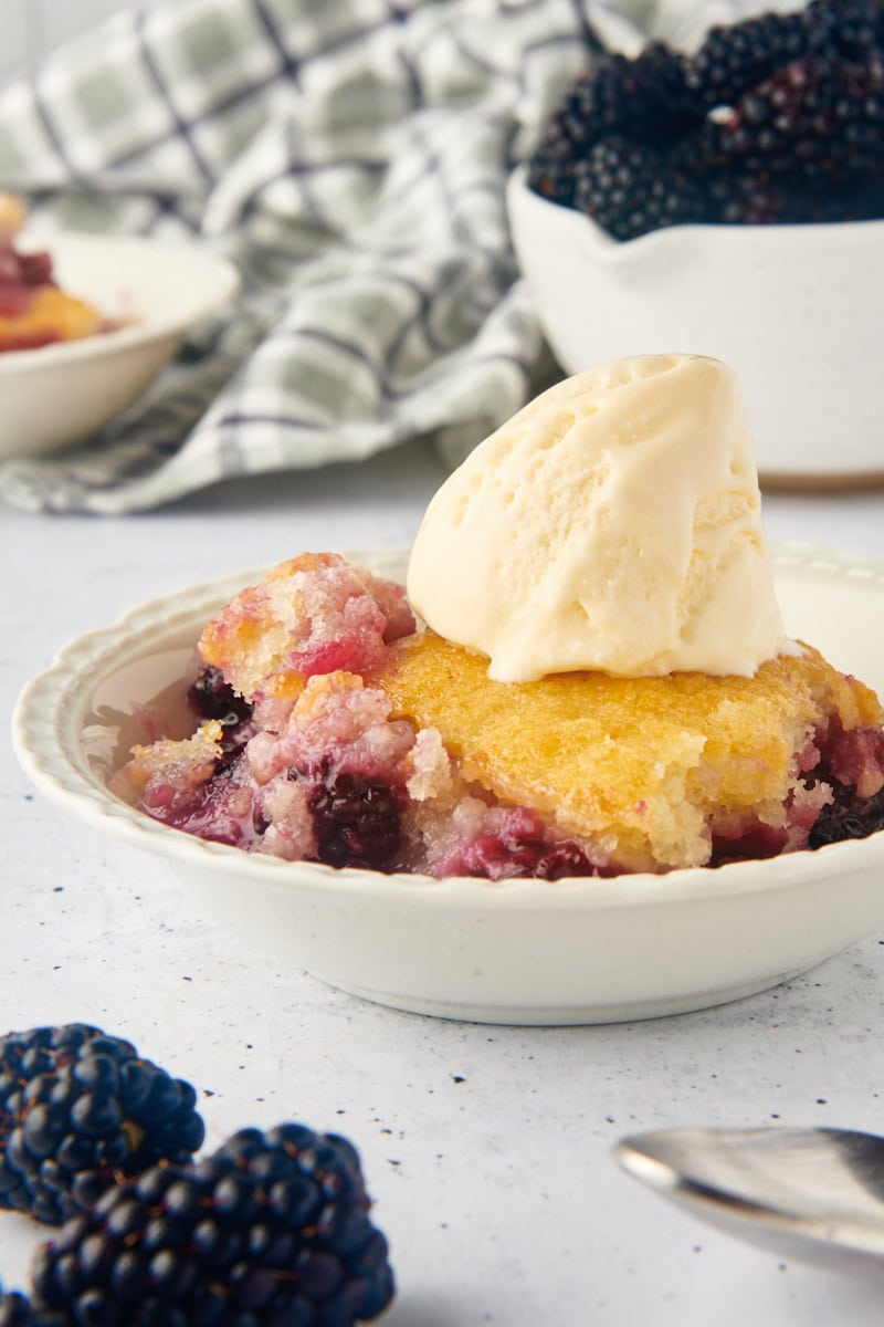 blackberry cobbler in a white bowl topped with ice cream