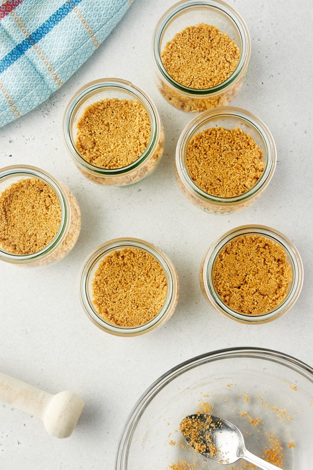 overhead view of graham cracker crusts in the bottom of individual jars