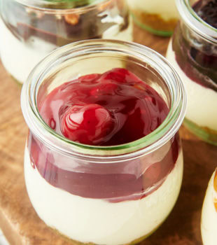 close-up view of a no-bake cheesecake jar topped with cherry pie filling