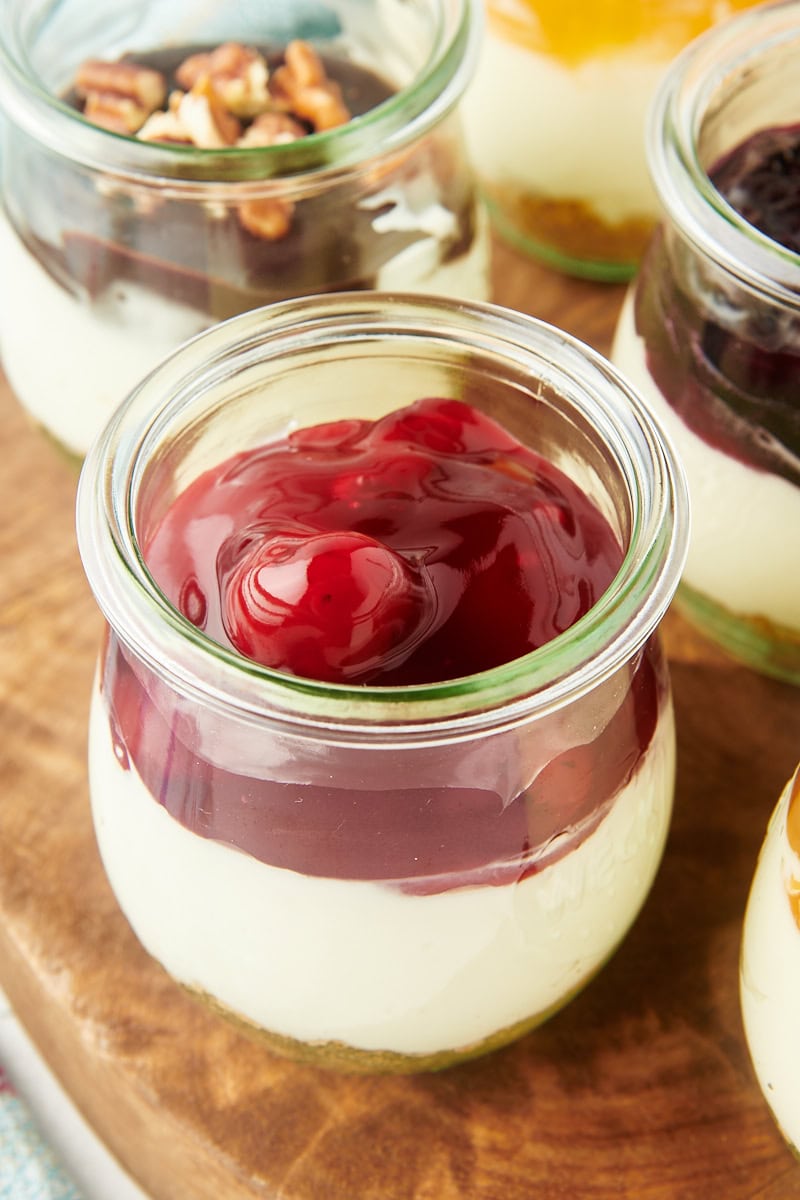 close-up view of a no-bake cheesecake jar topped with cherry pie filling