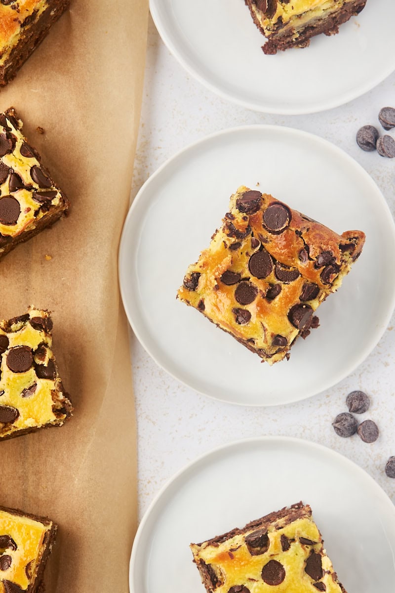 overhead view of chocolate chip cheesecake brownies on white plates