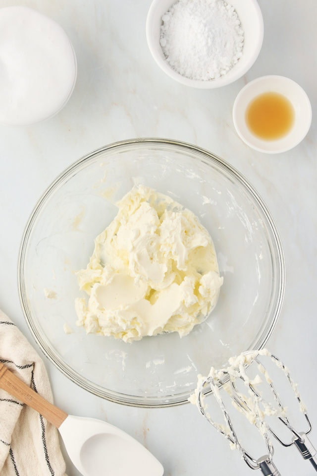 overhead view of beaten cream cheese in a glass mixing bowl